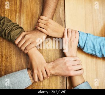United through their diversity. High angle shot of a group of unrecognizable university students holding one anothers wrists as a show of solidarity. Stock Photo