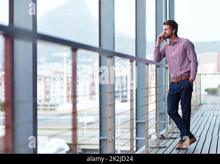 Sustaining business relationships over the phone. Shot of a young businessman talking on a phone outside of an office building. Stock Photo