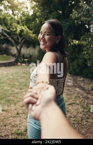 Our love is an adventure. Shot of an attractive young woman holding her boyfriends hand and leading the way while on an outdoor date. Stock Photo