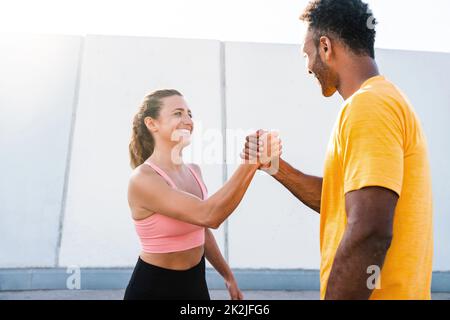 Interracial sportive couple training outdoors - Multiracial couple wearing sportswear and doing functional workout outdoors to strenght body muscles, Stock Photo