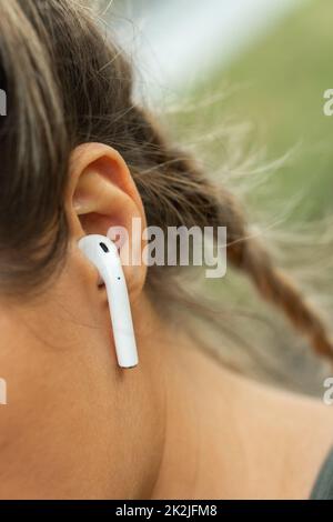 Female ear with wireless earbud Stock Photo