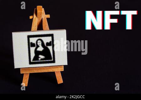 Digital Work of Art on a Easel Together with the Writing NFT in Bold Letters Stock Photo
