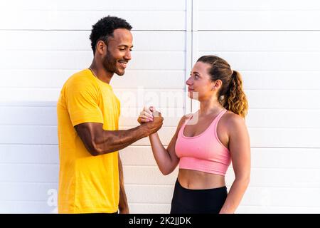 Interracial sportive couple training outdoors - Multiracial couple wearing sportswear and doing functional workout outdoors to strenght body muscles, Stock Photo