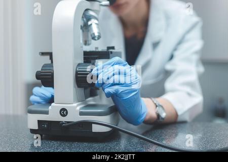 Woman scientist researching with microscope in laboratory Stock Photo