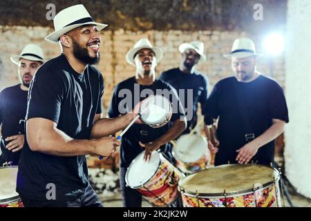 Feeling the rhythm in the drums. Shot of a group of musical performers playing together indoors. Stock Photo