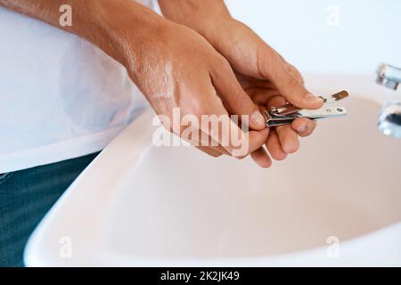 Long fingernails can harbor lots of dirt and bacteria. Closeup shot of an unrecognizable man cutting his nails at a basin. Stock Photo