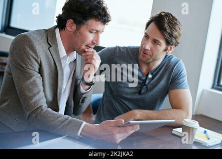 Working wirelessly. two handsome businessmen working on a digital tablet. Stock Photo