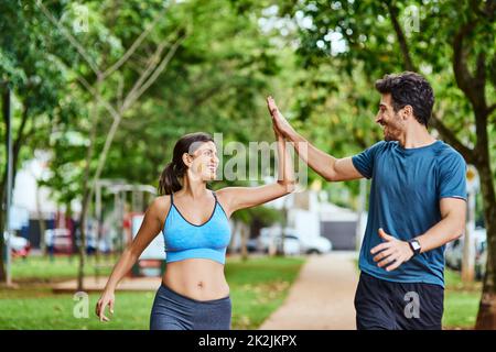 Thats just what we needed to get our hearts racing. Shot of a sporty young couple high fiving while exercising outdoors. Stock Photo