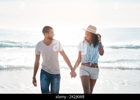 Im so happy to have you in my life. Shot of a young couple walking along the beach. Stock Photo