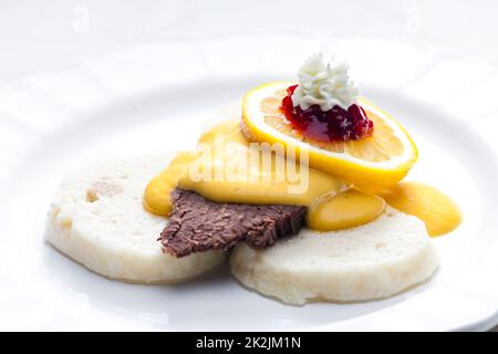 sirloin cream sauce with dumplings served with lemon, cranberries and whipped cream Stock Photo