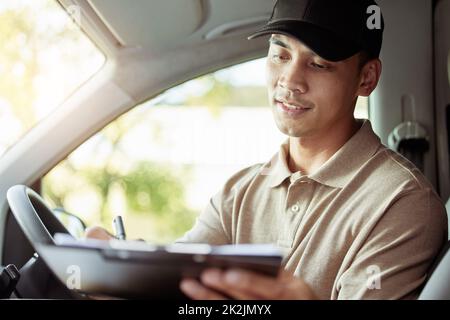 Making sure that all of my info is correct. Shot of a delivery man checking the paperwork for his delivery in his car. Stock Photo