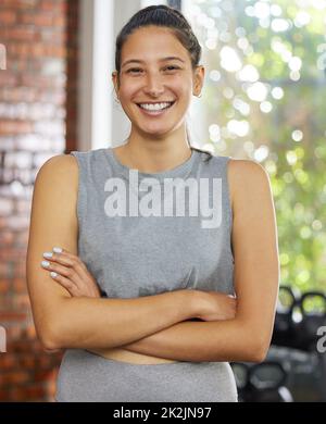 Organise your life around your dreams. Shot of a young woman posing and smiling in a gym. Stock Photo