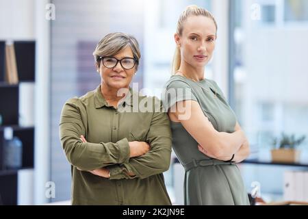 Were the women leading the business. Shot of two businesswomen standing together in the office with their arms folded. Stock Photo