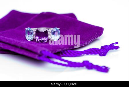 Amethyst with blue topaz and white sapphire Jewel or gems ring on violet velvet bag. Collection of natural gemstones accessories. Studio shot Stock Photo