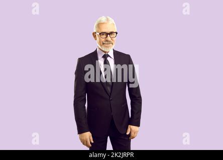 Senior man in formal suit posing at camera, smiling, isolated on purple background Stock Photo