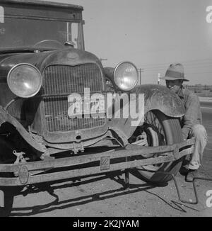 Migrant worker from Oklahoma repairing tire on California highway By Dorothea Lange, 1895-1965 dated 1936  Feb. Stock Photo