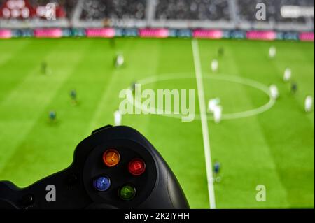 Game controller in front of a screen with a soccer video game Stock Photo