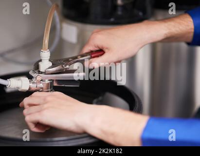 Skilled hands working on your water heating system. Cropped shot of a handyman repairing a pipe on a water heater. Stock Photo