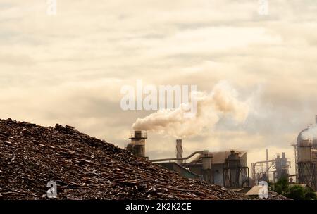 Pile of brown bottle for recycle in recycling factory. Glass waste for recycle. CO2 emissions. Carbon dioxide greenhouse gas emissions from factory chimneys. Smoke from chimneys. Air pollution concept Stock Photo