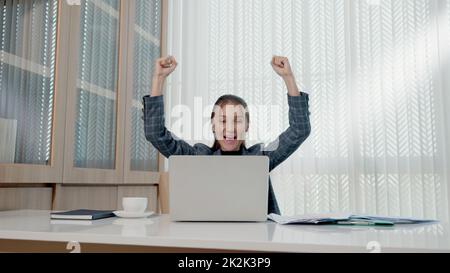 Happy business woman excited surprised work at white office desk with pc laptop throwing up paper account documents Stock Photo