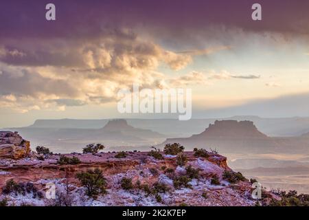 Storm clouds over Elaterate Butte, left, and Ekker Butte, right, from Candlestick Tower Overlook, Canyonlands NP, Utah.  Orange Cliffs behind in the G Stock Photo