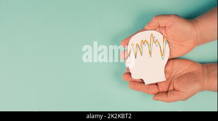 Holding a head in the hands, mental health concept, alzheimer and epilepsy disorder, brain waves, paper cut out Stock Photo