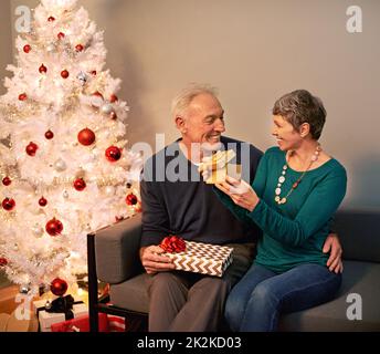 Its perfect. a happy mature couple exchanging gifts on Christmas eve. Stock Photo