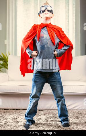 Proud young Super Hero posing in a red cape and goggles Stock Photo