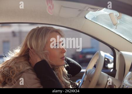 Dangerous young woman driver fluffing up her hair Stock Photo
