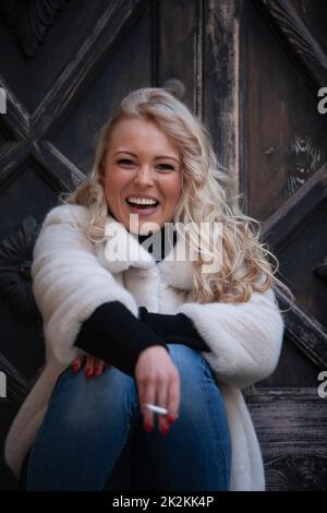 vivacious blond woman smoking outdoors Stock Photo