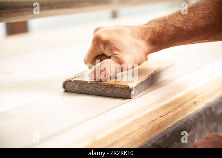 Unidentifiable man sanding large piece of wood Stock Photo