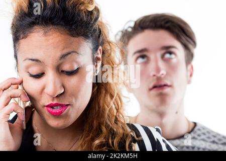 Bored man standing behind woman talking on phone Stock Photo
