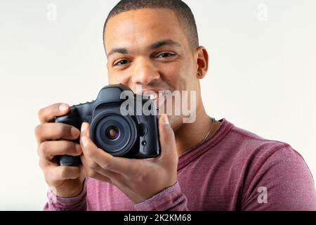 Photographer smiling as he holds up his camera to the viewer Stock Photo