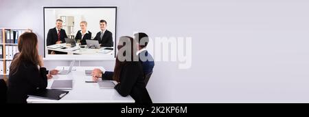 Group Of Businesspeople Looking At Projector With Laptop On Desk In Office Stock Photo
