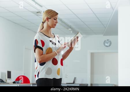 Businesswoman standing using a handheld tablet pc in the office Stock Photo