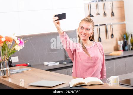 Pretty young woman taking a selfie in the kitchen Stock Photo