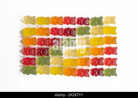 top view of multi-colored gummy bears arranged in rows by color as a gradient on a light background with negative space close-up Stock Photo