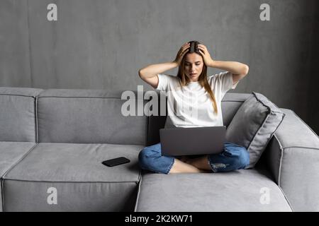 Shocked young woman looking at laptop computer screen at home unpleasantly surprised by email notification message reading bad news online about debt, Stock Photo