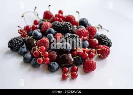 A bunch of red currants, raspberries, blueberries, blackberries on a light background Stock Photo