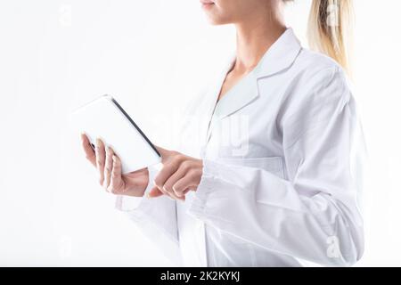 Woman in a white lab coat using a handheld tablet pc Stock Photo