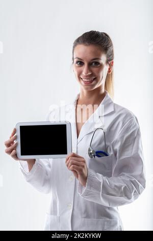 Smiling friendly doctor holding up a blank tablet pc Stock Photo