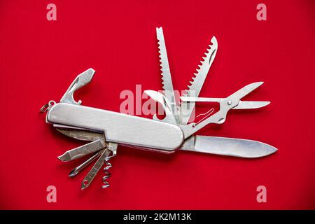 Metallic swiss knife isolated on red Stock Photo