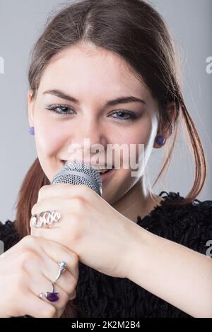 girl holding a microphone and singing Stock Photo