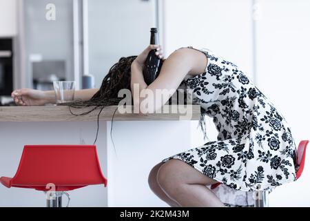 Drunk young woman passed out on a kitchen counter Stock Photo
