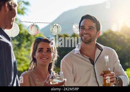 We can always make time for friends. Shot of a group of happy young friends hanging out at a backyard dinner party. Stock Photo
