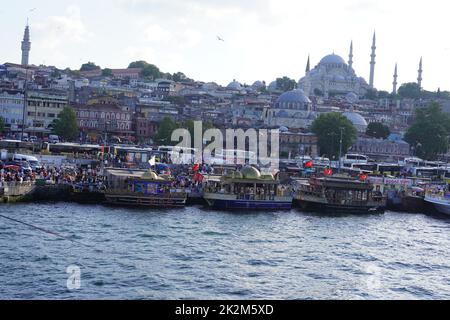 ISTANBUL, TURKEY - August 2, 2022: People crowd walking on Eminonu bazaar and pier dock full of ferrys and restaurants on a boats Stock Photo