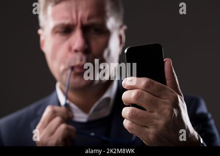 worried mature man with a smartphone Stock Photo