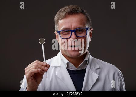 Confident dentist showing a dental mirror for regular check-up Stock Photo