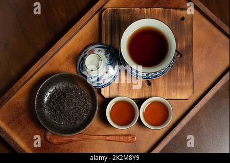chinese traditional porcelain tea cup and tea leaf on wooden ancient board Stock Photo