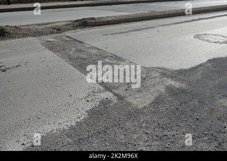 damaged and repaired asphalt road, damaged patched asphalt road Stock Photo